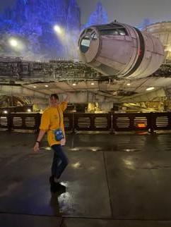 一个穿着t恤和裤子的人站在《星球大战》电影中的宇宙飞船前的画面